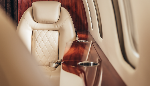 closeup of private jet interior with leather seats and wood details